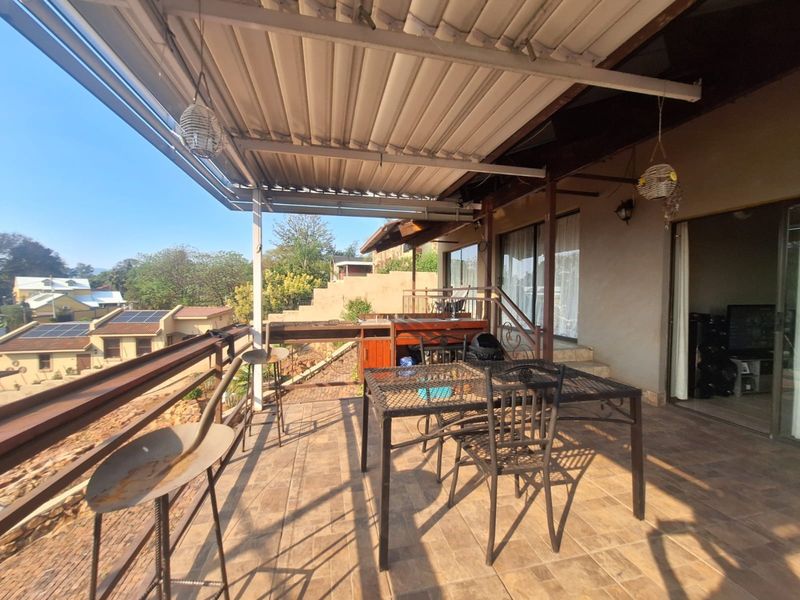 A spacious covered patio featuring tiled flooring, a built-in outdoor counter, and metal railings, offering an ideal space for outdoor dining and relaxation.