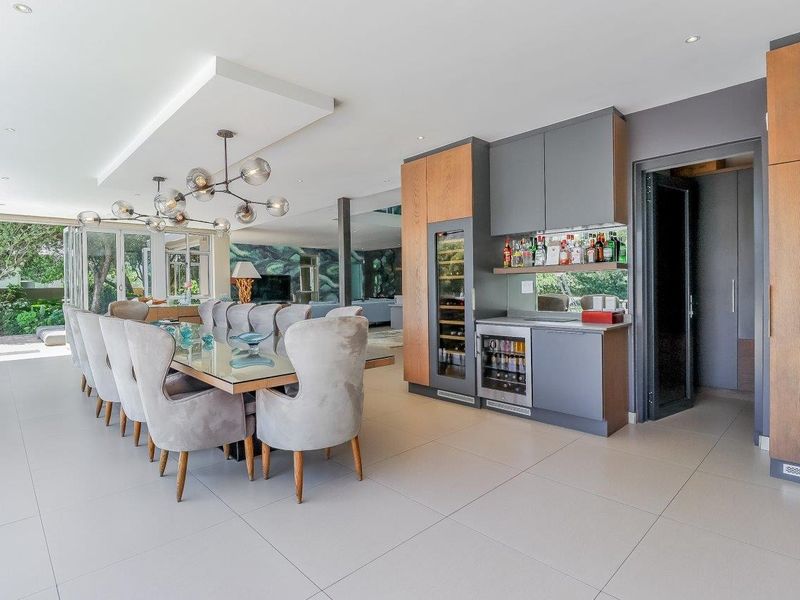 Spacious open-plan dining area featuring a modern built-in bar with integrated wine and beverage coolers, sleek cabinetry, and seamless access to the outdoor patio.