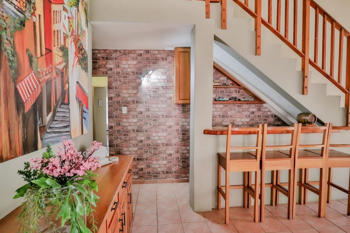 Interior view featuring a staircase with wooden balustrades, a brick-style feature wall, and a built-in breakfast bar area with tiled flooring.