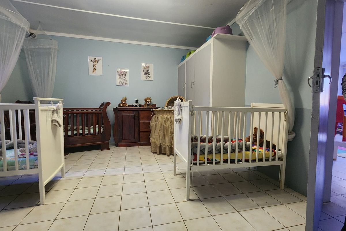 A spacious bedroom featuring tiled flooring and built-in cabinetry, currently utilized as a nursery.