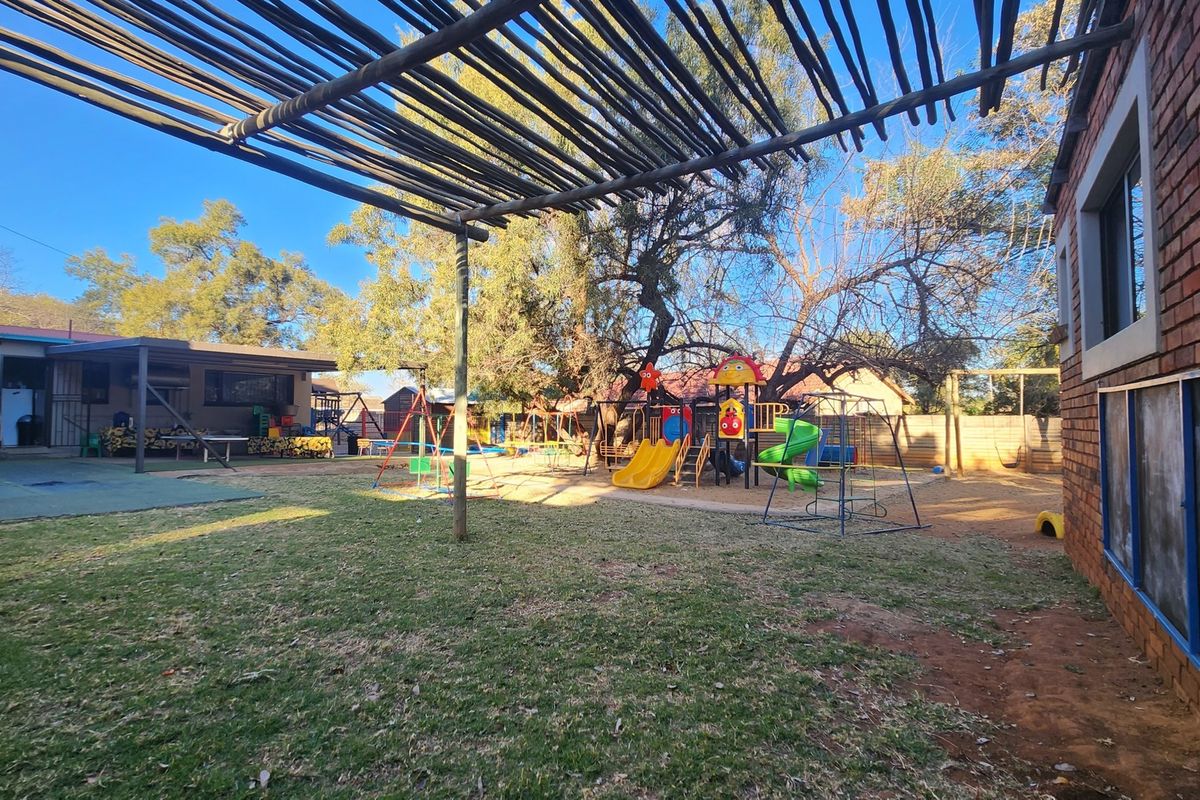 Spacious rear garden area featuring a timber pergola structure, established trees, and a dedicated play area with fixed playground equipment.