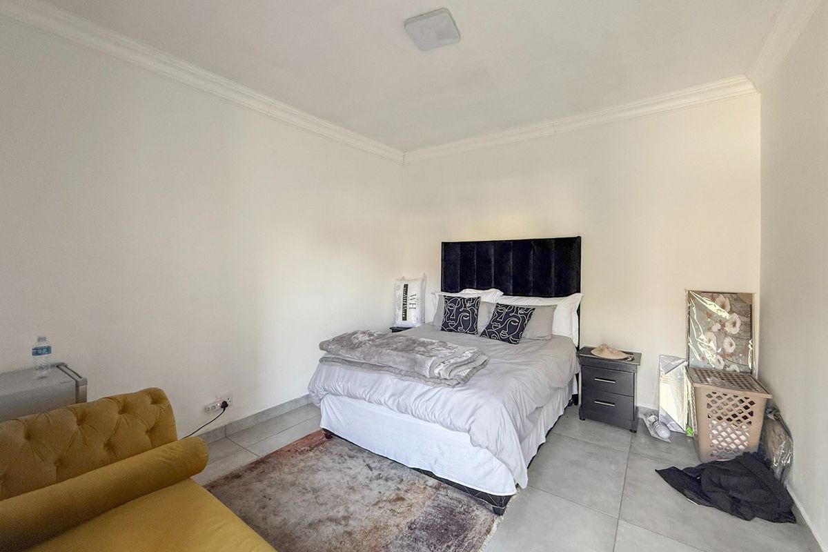 A bedroom featuring tiled flooring, crown molding, and a central ceiling light fixture.