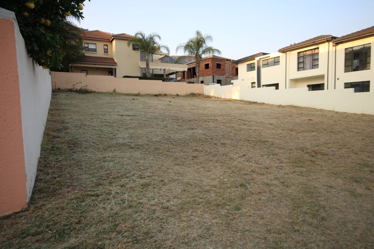 A vacant residential plot of land enclosed by perimeter boundary walls, situated within an established residential neighborhood.