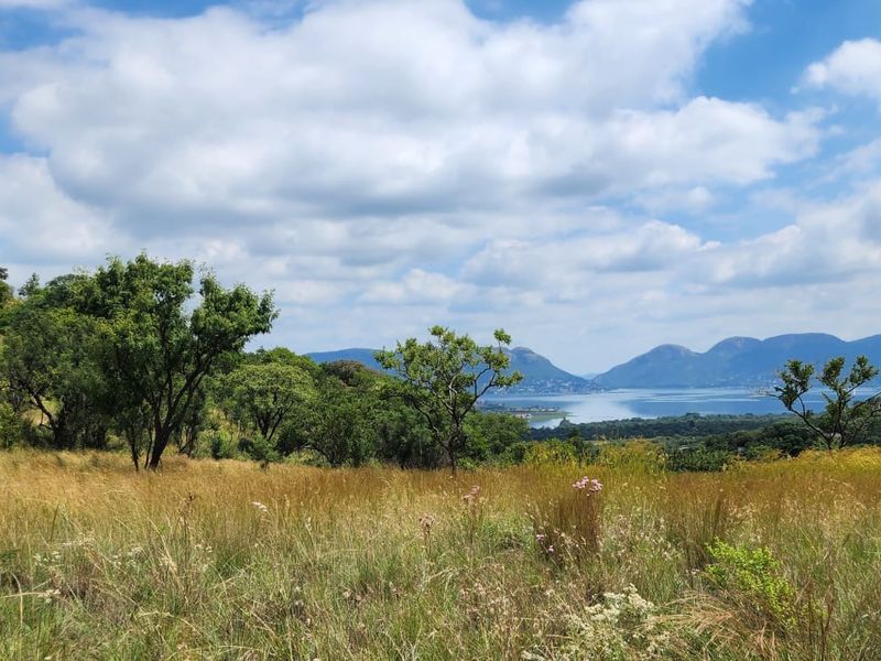 A scenic landscape view overlooking a valley, lake, and distant mountains, showcasing the natural beauty and expansive terrain of the small holding.