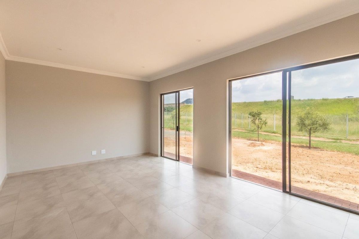 A bright, empty living area featuring neutral tiled flooring, coved ceilings, and large sliding glass doors that provide direct access to the rear garden.