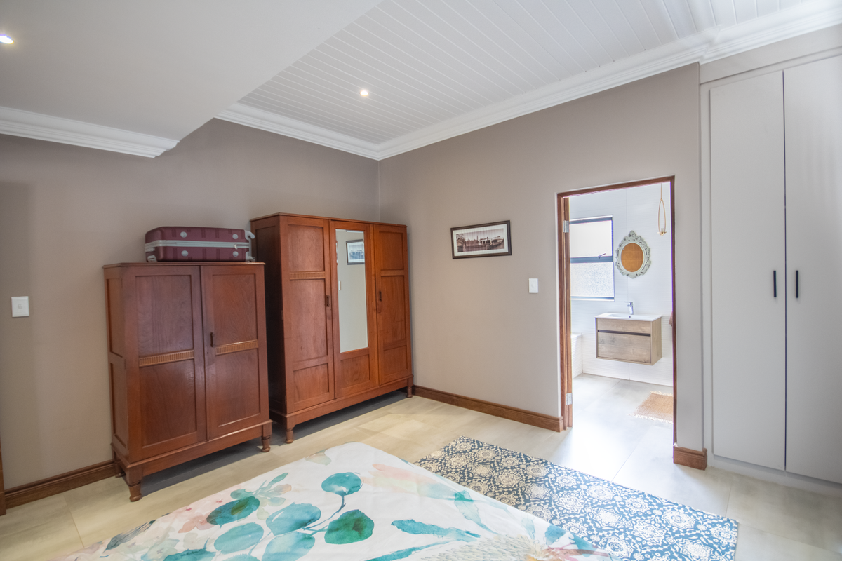 A well-maintained bedroom featuring built-in cabinetry, recessed ceiling lighting, and an adjoining en-suite bathroom with a modern vanity.