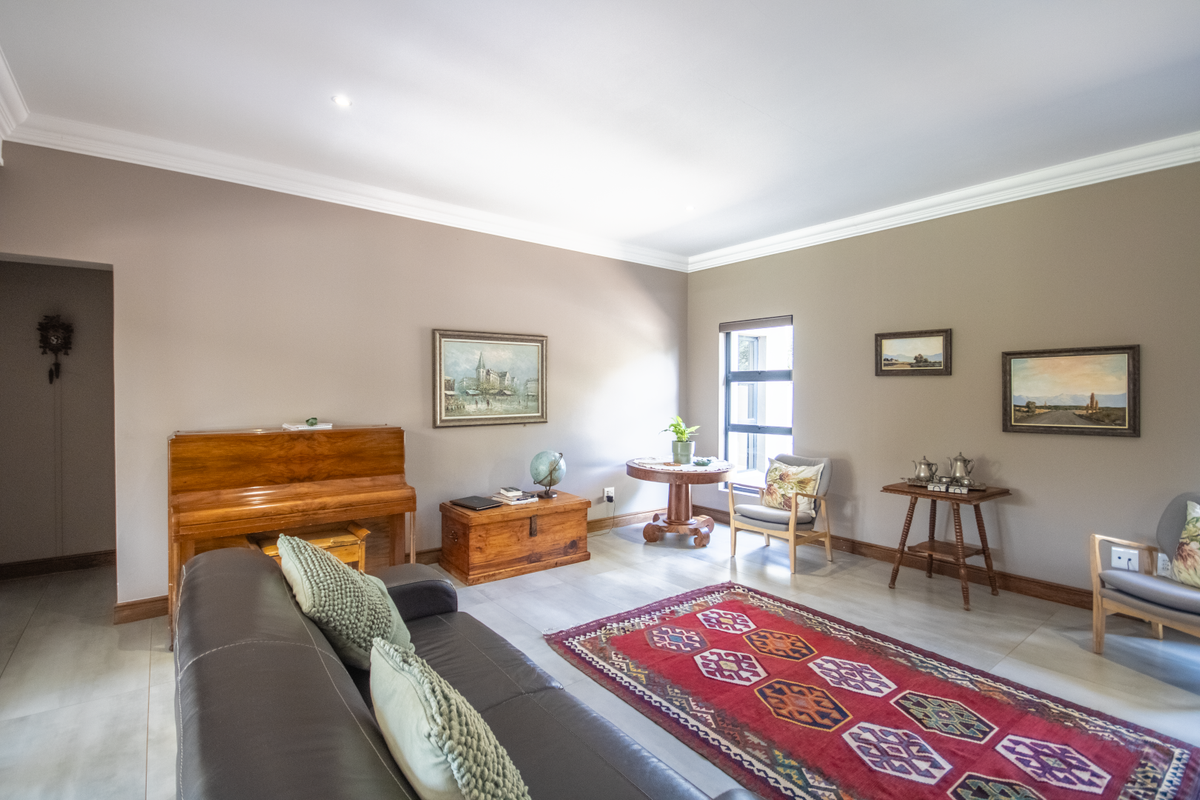 A spacious living room featuring neutral wall tones, tiled flooring, and crown molding, providing a comfortable and well-maintained area for relaxation.
