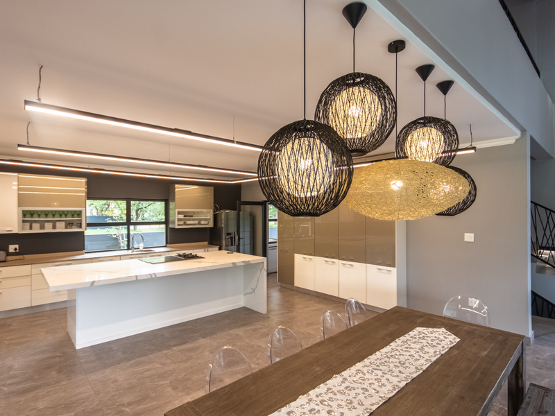 Modern open-plan kitchen featuring a large central island with stone countertop, sleek cabinetry, integrated appliances, and stylish pendant lighting over the dining area.