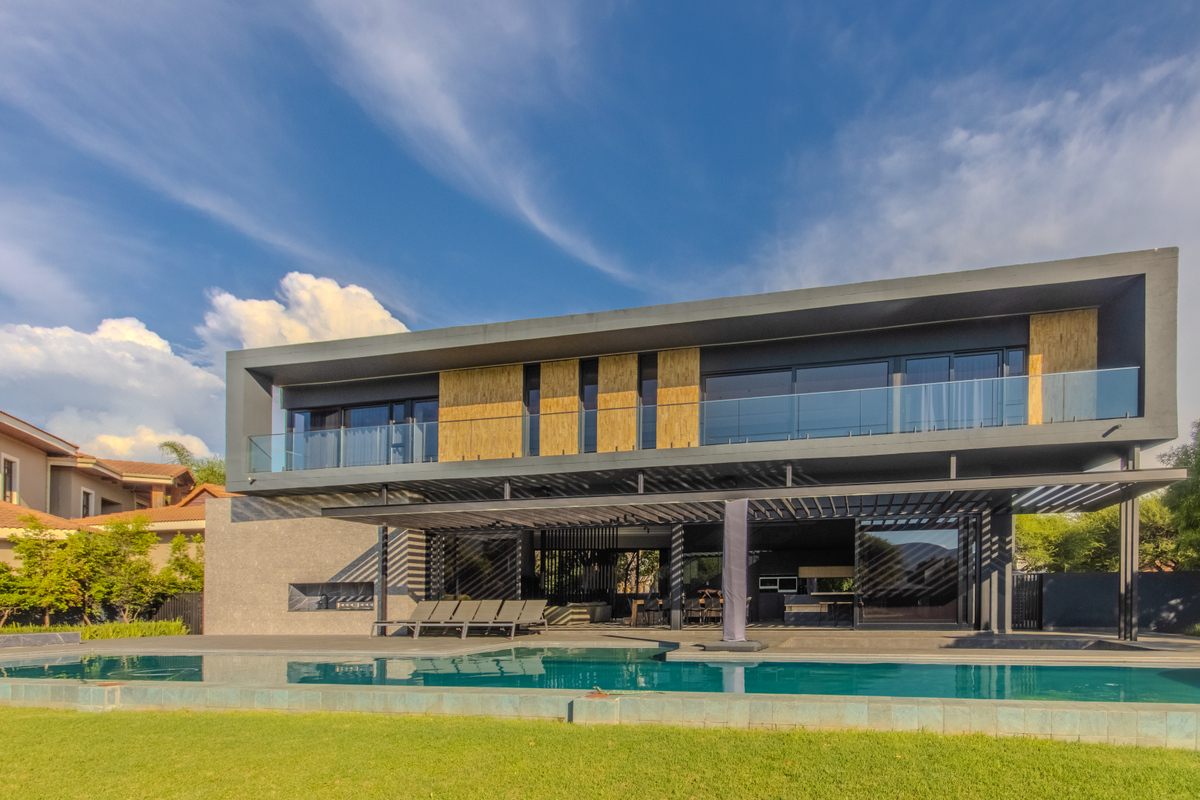 Modern double-story residence featuring a sleek architectural design, expansive glass balconies, a covered patio, and a private swimming pool set in a landscaped garden.