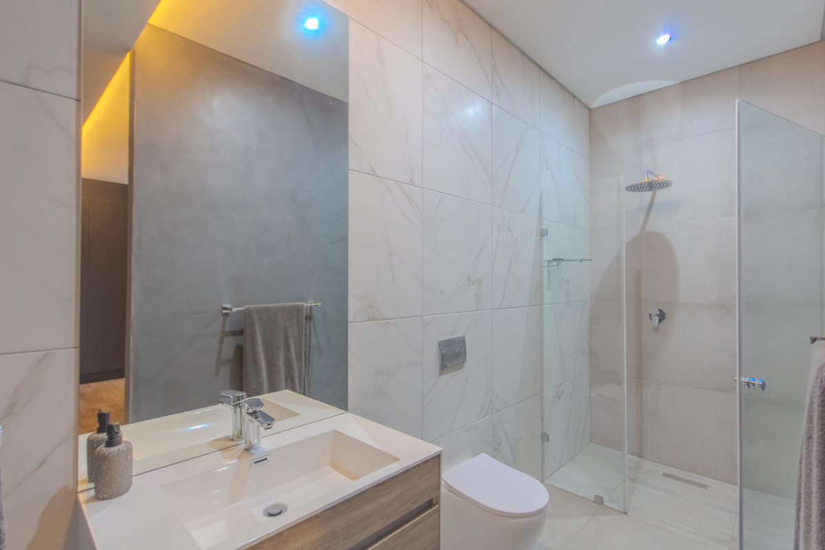 Modern bathroom featuring a floating vanity, wall-mounted toilet, and a spacious walk-in shower with glass enclosure and contemporary marble-look wall tiling.