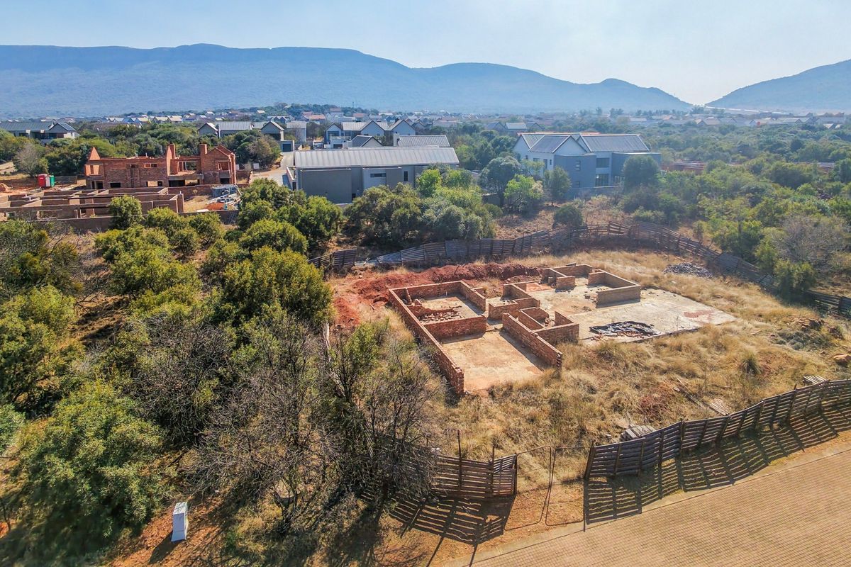 Aerial view of a residential vacant land plot featuring an incomplete brick foundation and concrete slab within a developed estate setting.