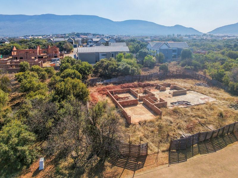 Aerial view of a residential vacant land plot featuring an incomplete brick foundation and concrete slab within a developed estate setting.