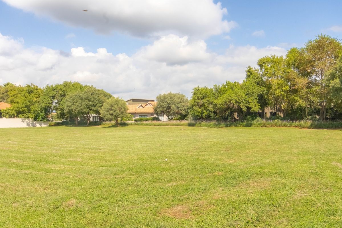 A spacious, well-maintained vacant residential plot featuring lush green lawn and mature trees, offering a peaceful setting for future development.