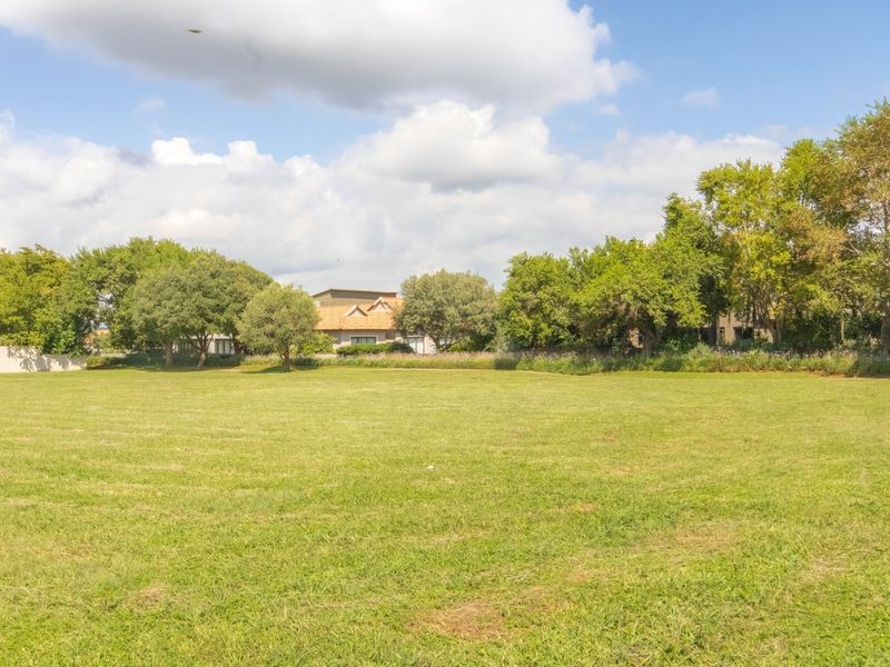 A spacious, well-maintained vacant residential plot featuring lush green lawn and mature trees, offering a peaceful setting for future development.