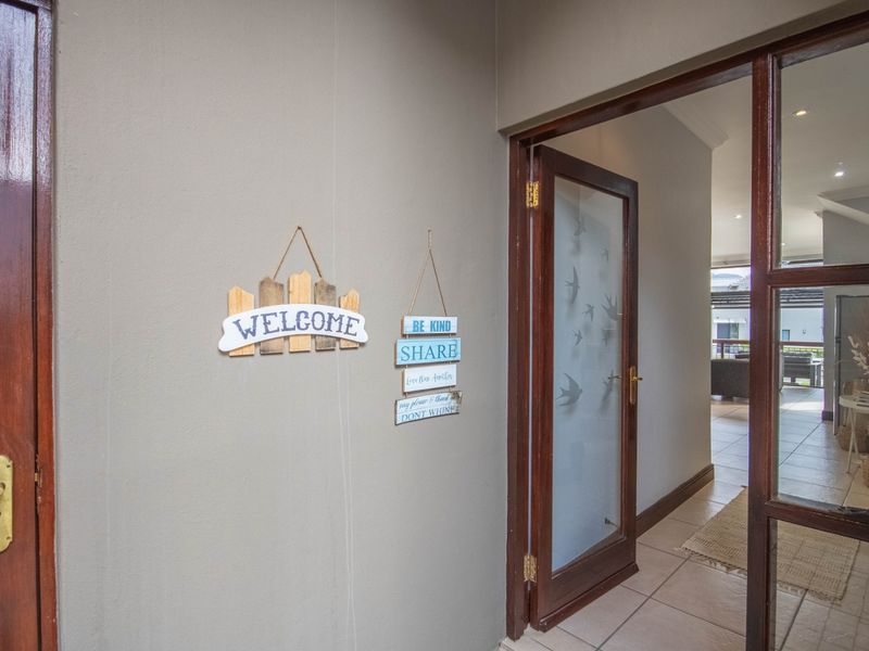A welcoming entrance area featuring tiled flooring, a frosted glass panel door, and a clear view into the open-plan living space.