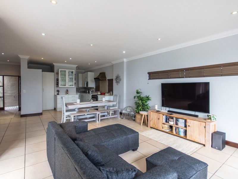 Spacious open-plan living area featuring tiled floors, recessed lighting, and a functional kitchen with built-in cabinetry and appliances.