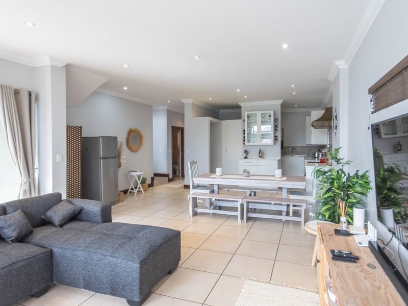 Spacious open-plan living and dining area featuring tiled flooring, recessed lighting, and a functional kitchen with built-in cabinetry.