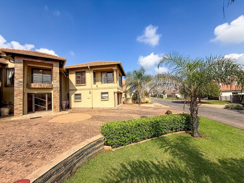 Front elevation of a multi-story residential property featuring stone cladding, a paved driveway, and a balcony.