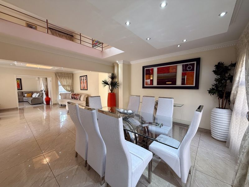 Spacious open-plan dining area featuring polished tiled floors, recessed lighting, and a mezzanine level overlooking the living space.