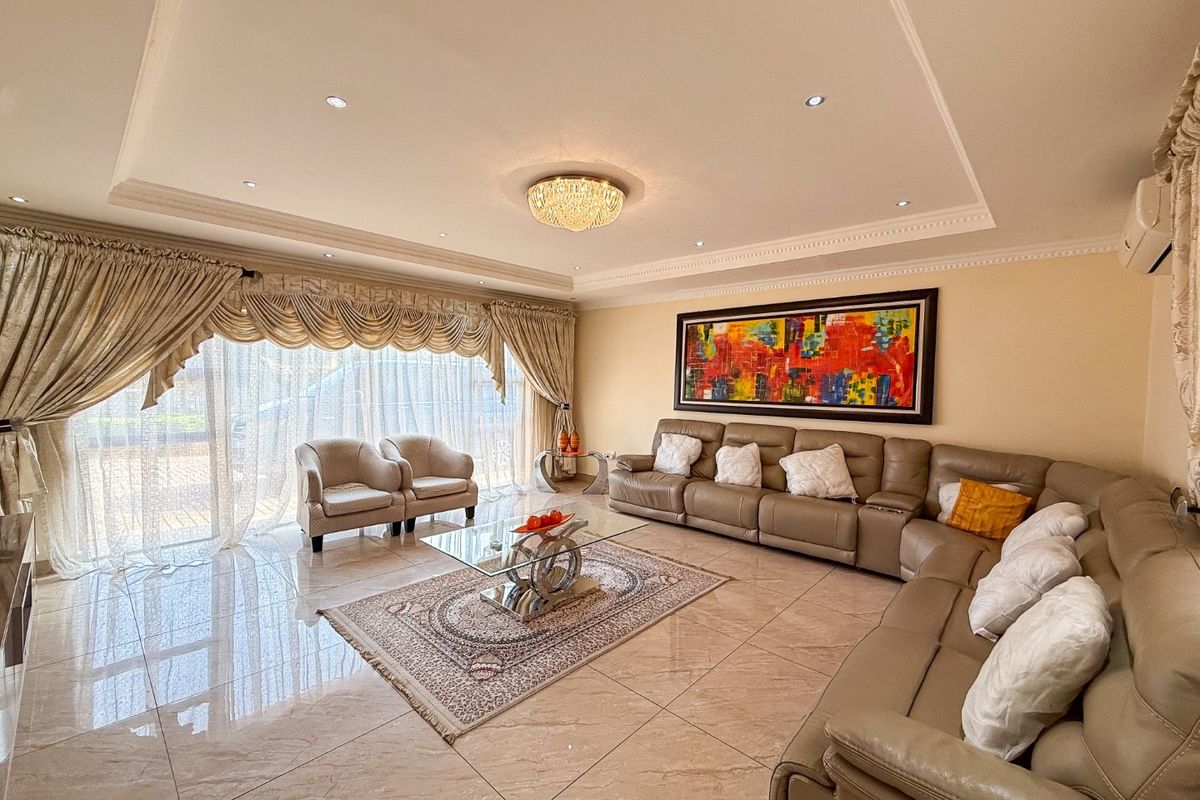 A spacious living room featuring polished tile flooring, a recessed ceiling with cove lighting, and large sliding glass doors providing natural light.