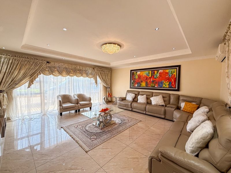A spacious living room featuring polished tile flooring, a recessed ceiling with cove lighting, and large sliding glass doors providing natural light.