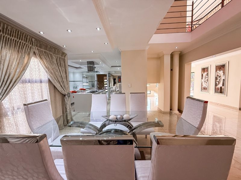 Spacious open-plan dining area featuring tiled floors, recessed lighting, and a view through to the modern kitchen and staircase.