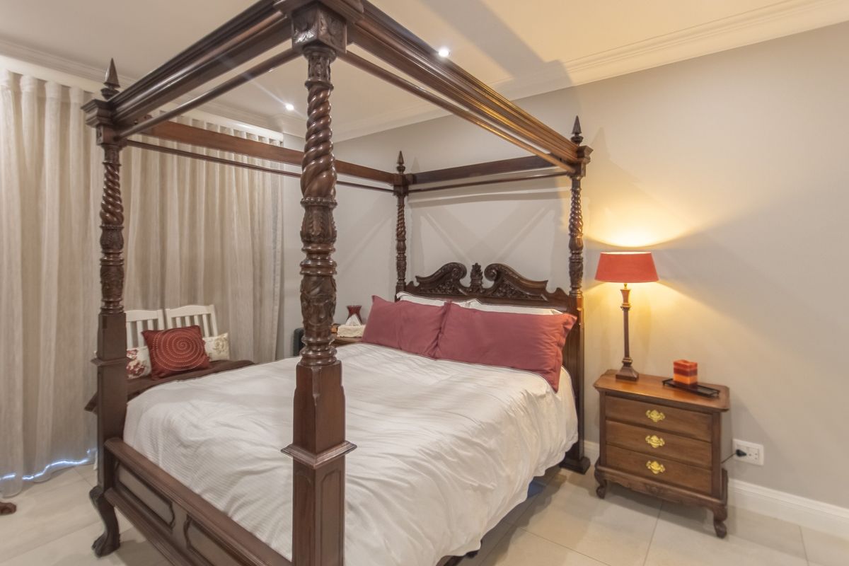 A well-maintained bedroom featuring neutral wall tones, tiled flooring, and recessed downlighting, creating a comfortable and inviting sleeping space.