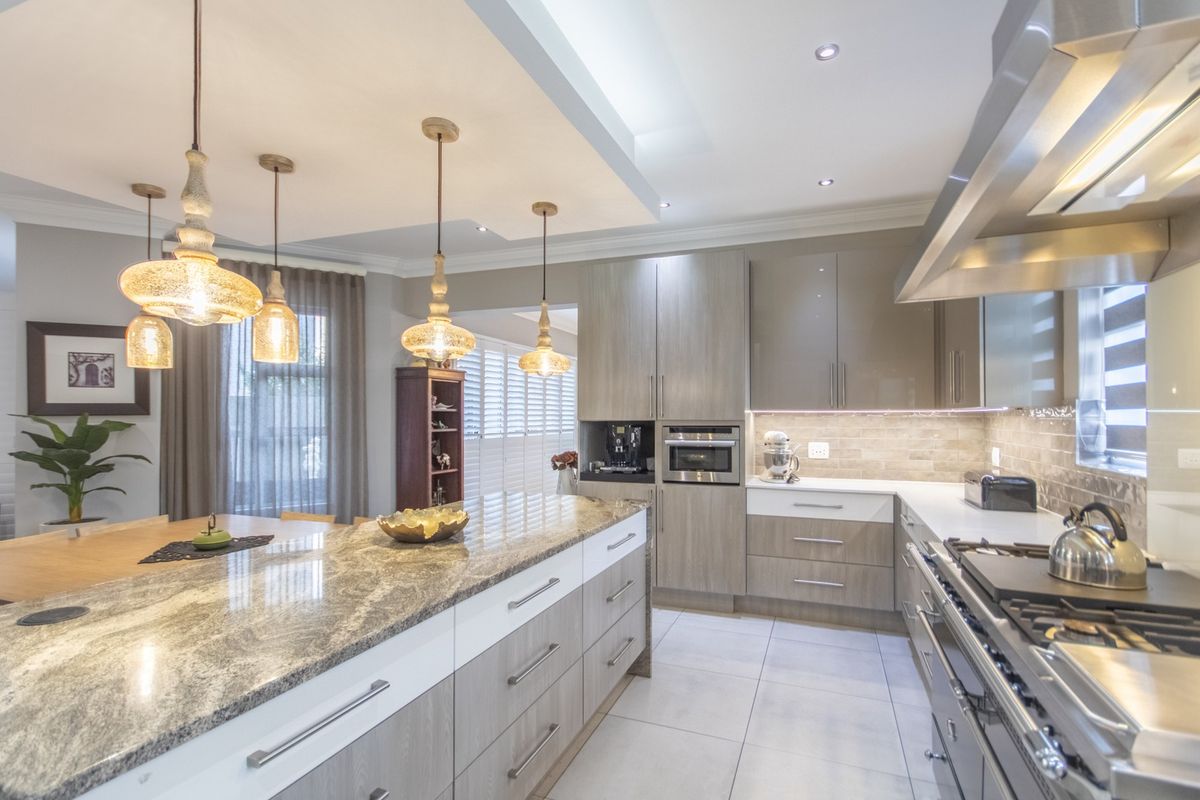 Modern kitchen featuring a large granite island, high-end built-in appliances, sleek cabinetry, and elegant pendant lighting, creating a sophisticated and functional culinary space.