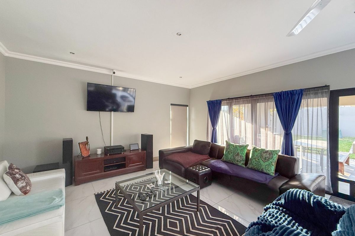 A spacious living room featuring tiled flooring, recessed lighting, a ceiling fan, and large sliding glass doors providing access to the outdoor area.