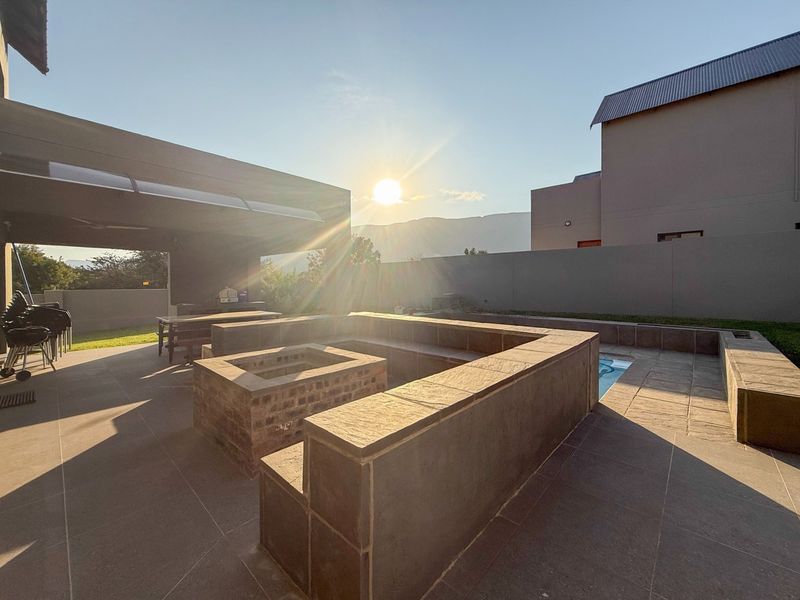 A spacious covered patio area featuring a built-in fire pit, integrated seating, and direct access to a swimming pool.