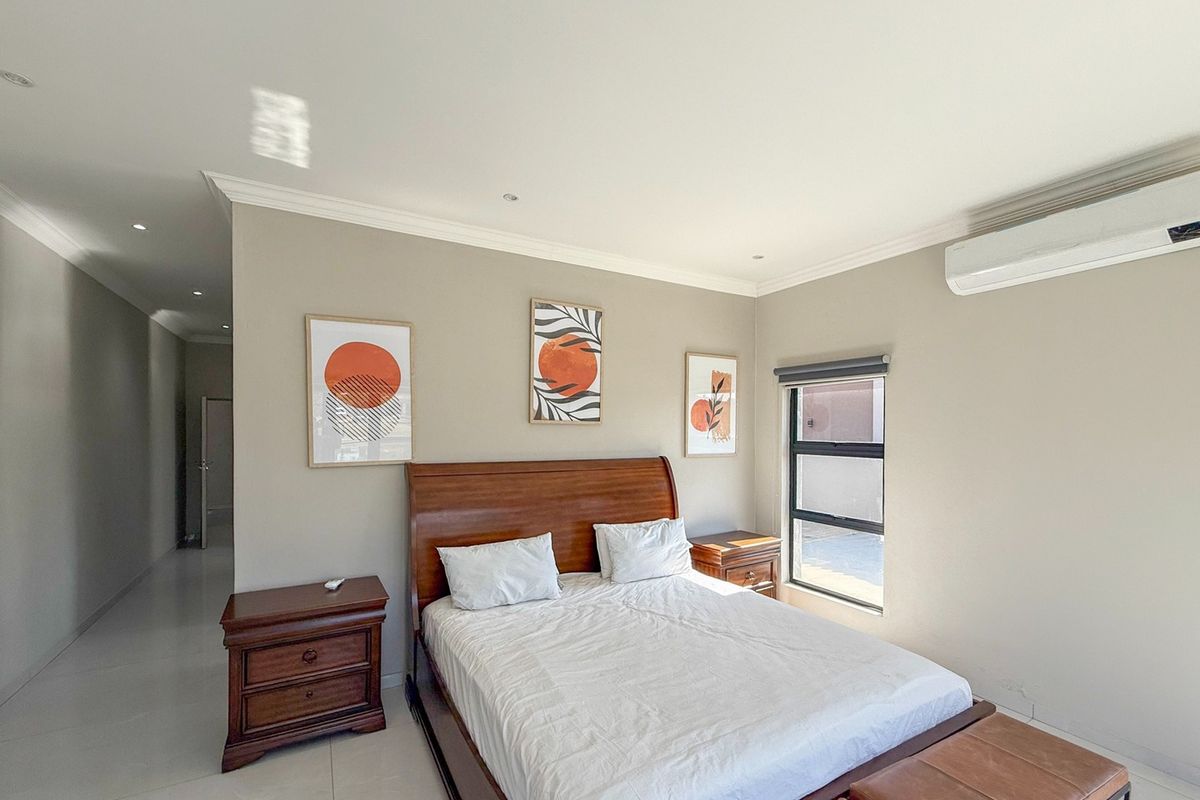 A well-maintained bedroom featuring neutral wall tones, tiled flooring, recessed lighting, and a wall-mounted air conditioning unit.