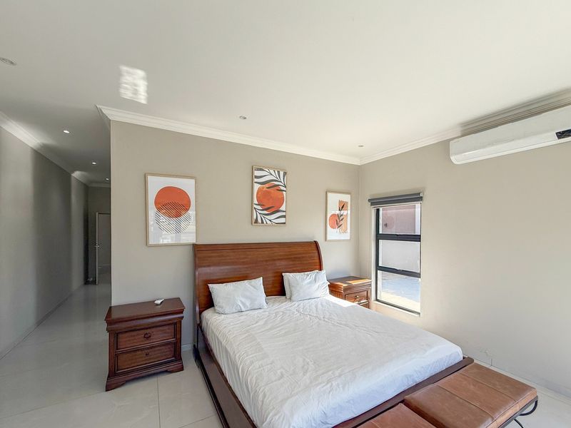 A well-maintained bedroom featuring neutral wall tones, tiled flooring, recessed lighting, and a wall-mounted air conditioning unit.