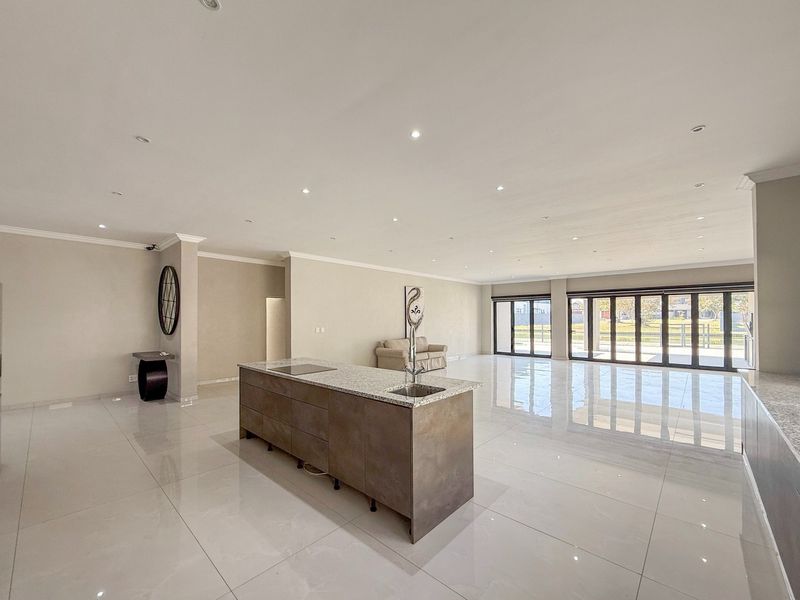 Spacious open-plan living area featuring a modern kitchen island with granite countertops, sleek cabinetry, and large stacking doors leading to the exterior.