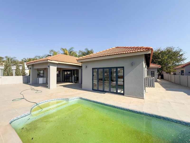 Rear exterior view featuring a tiled patio, swimming pool, and modern aluminium stacker doors leading into the home.