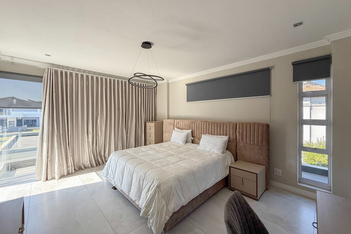 Spacious bedroom featuring large format floor tiles, modern recessed lighting, and floor-to-ceiling curtains with direct access to an outdoor area.