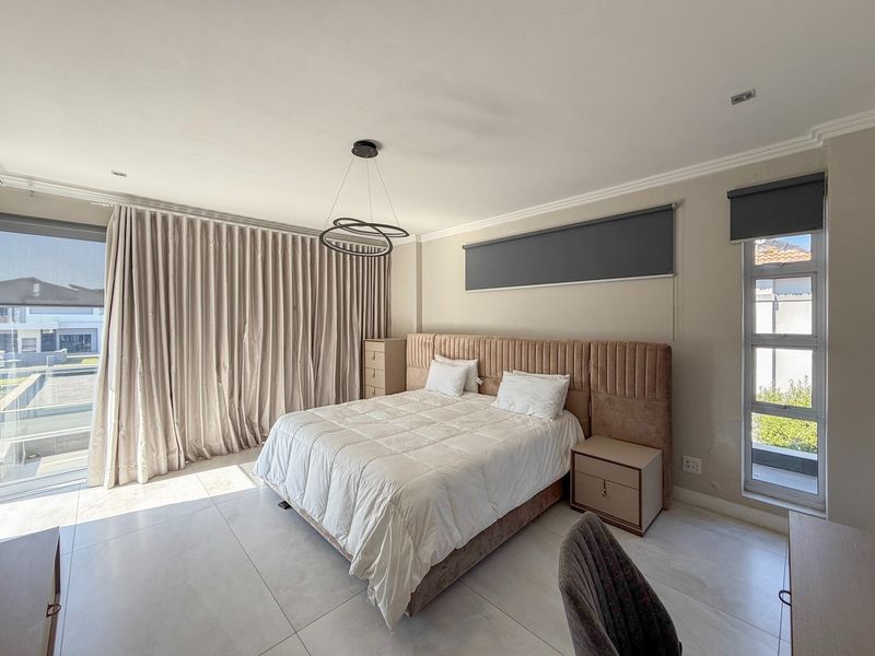 Spacious bedroom featuring large format floor tiles, modern recessed lighting, and floor-to-ceiling curtains with direct access to an outdoor area.