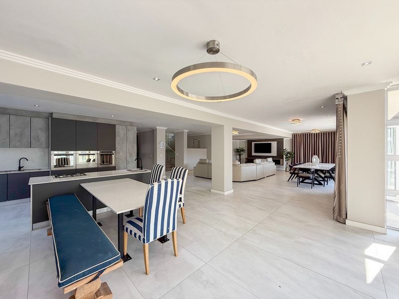 Spacious open-plan living area featuring a modern kitchen with integrated appliances, large format floor tiles, and contemporary lighting throughout.