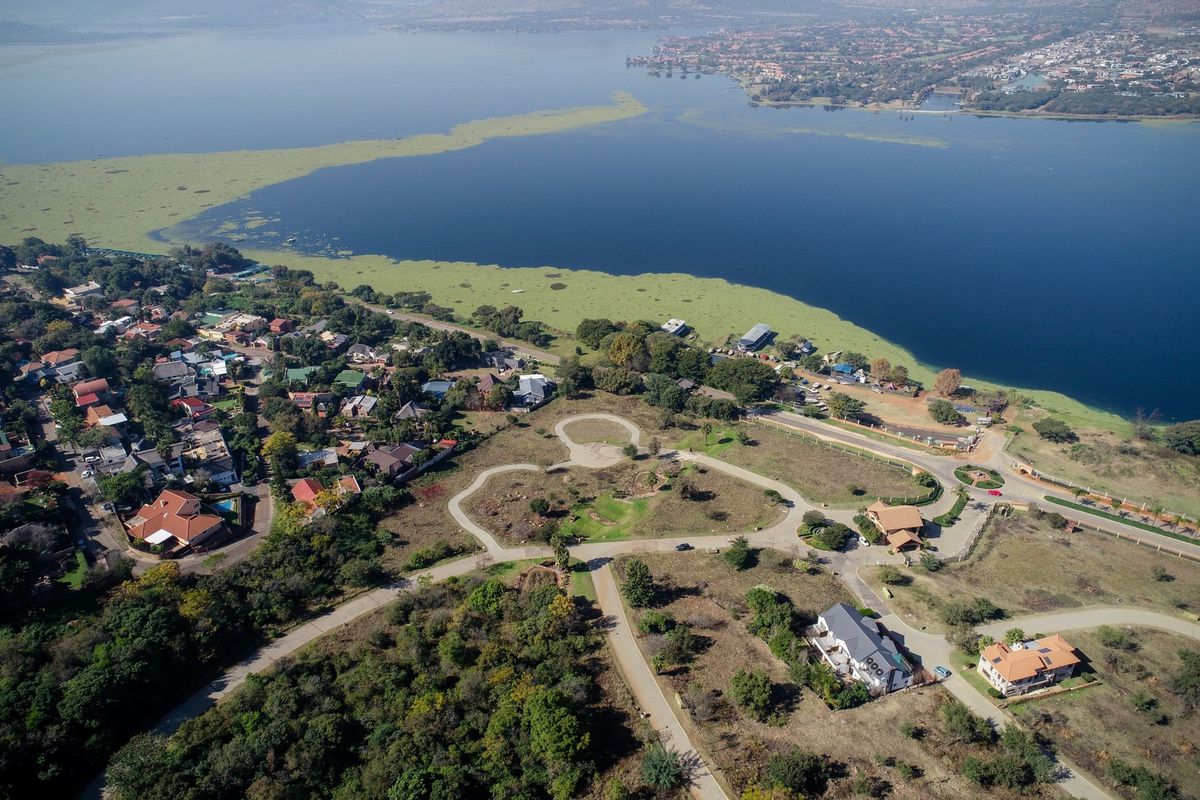 Aerial view of a vacant residential land parcel situated near a large lake, featuring established access roads and surrounding residential development.