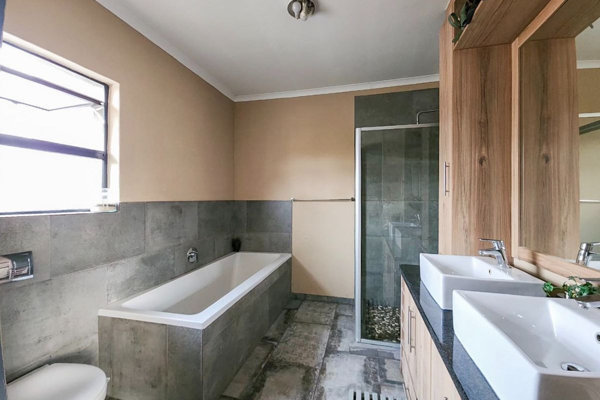 Modern bathroom featuring a double vanity with vessel sinks, a built-in bathtub, and a separate glass-enclosed shower with contemporary tile finishes.
