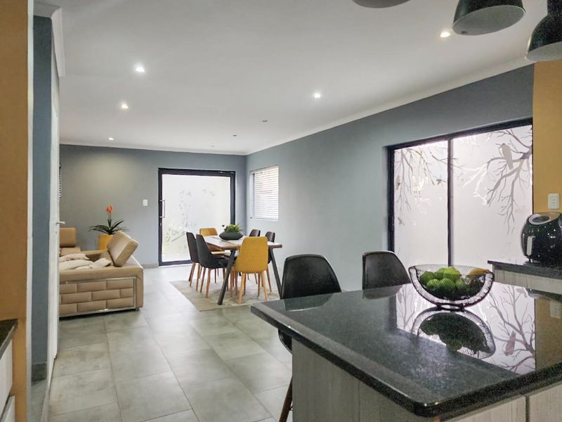 Spacious open-plan living and dining area featuring modern tiled flooring, recessed lighting, and seamless access to the outdoors through sliding glass doors.