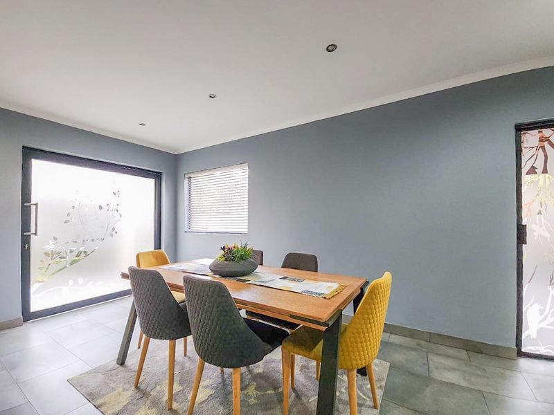 A bright dining room featuring tiled flooring, recessed downlights, and a sliding glass door providing natural light.