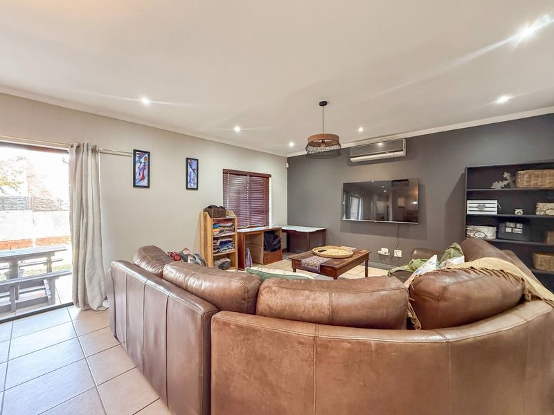 Spacious living room featuring tiled flooring, recessed downlighting, a wall-mounted air conditioner, and direct access to an outdoor patio area.