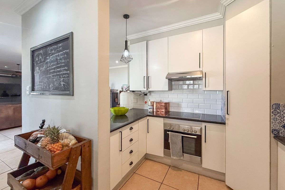 A compact, functional kitchen featuring white cabinetry, subway tile backsplash, stone countertops, and integrated stainless steel appliances.