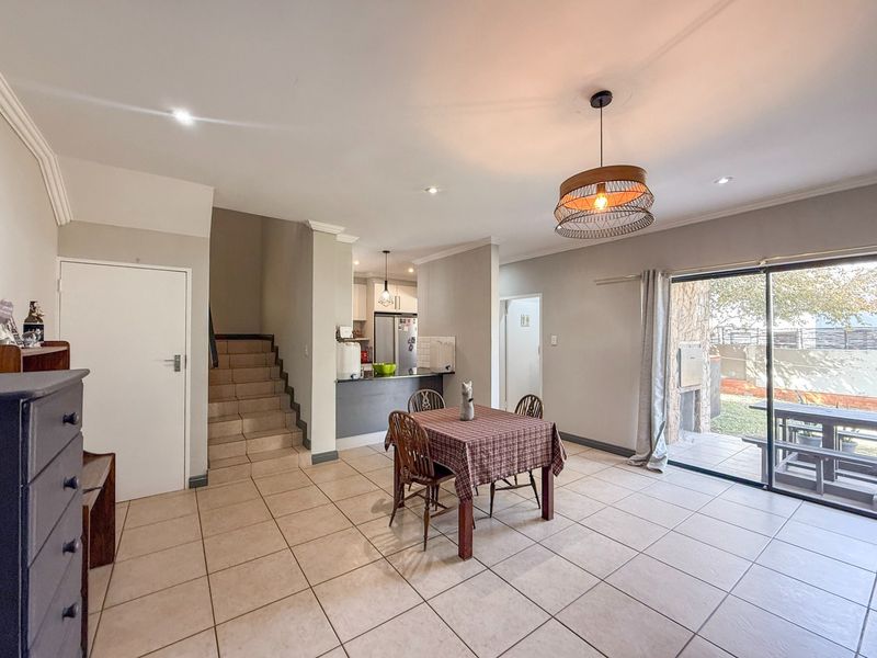 Open-plan living and dining area featuring tiled floors, recessed lighting, a staircase, and sliding glass doors leading to an outdoor patio area.
