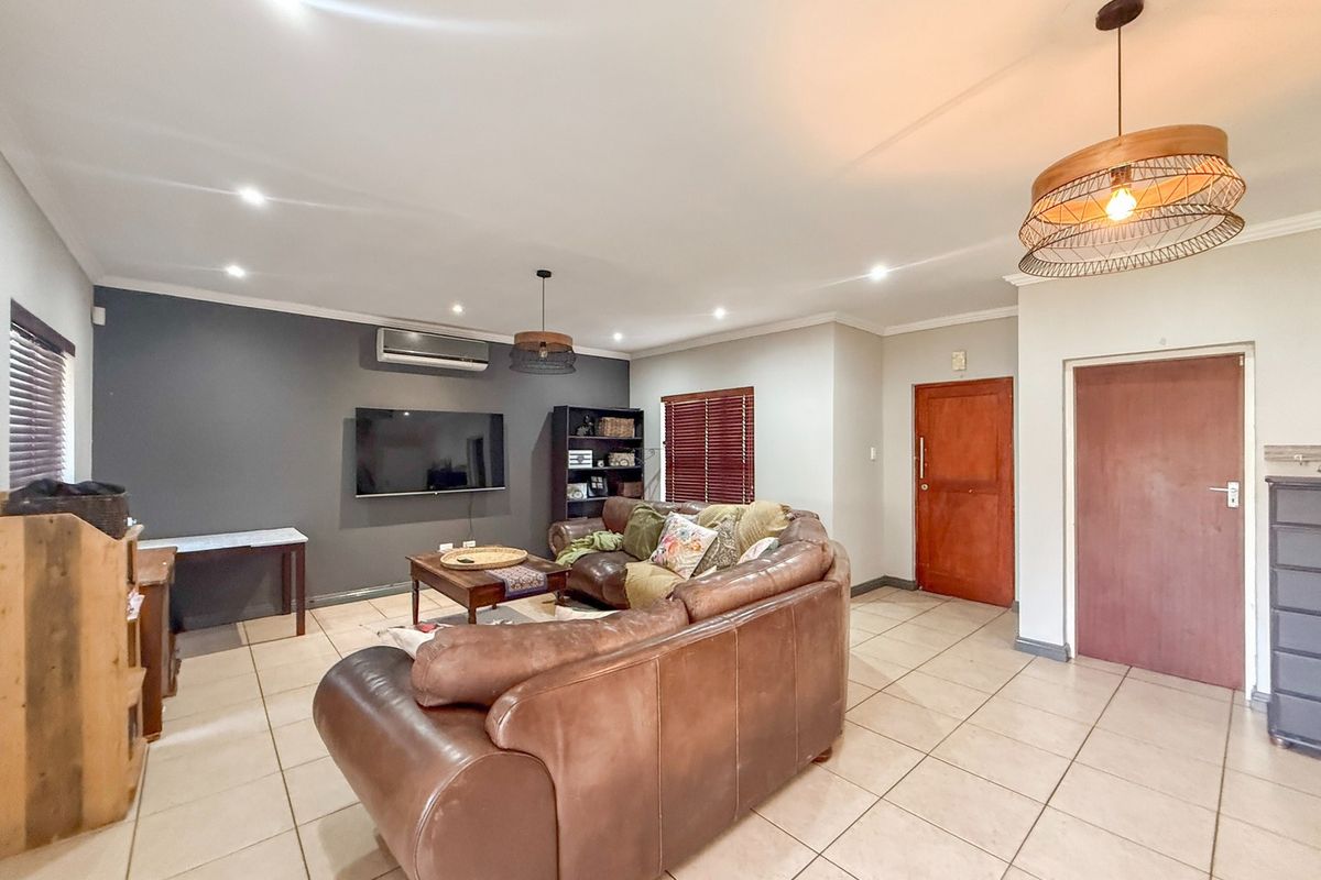 Spacious living room featuring tiled flooring, recessed downlighting, a split-system air conditioner, and timber venetian blinds.