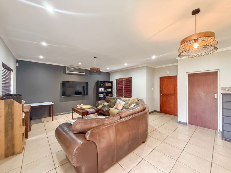 Spacious living room featuring tiled flooring, recessed downlighting, a split-system air conditioner, and timber venetian blinds.