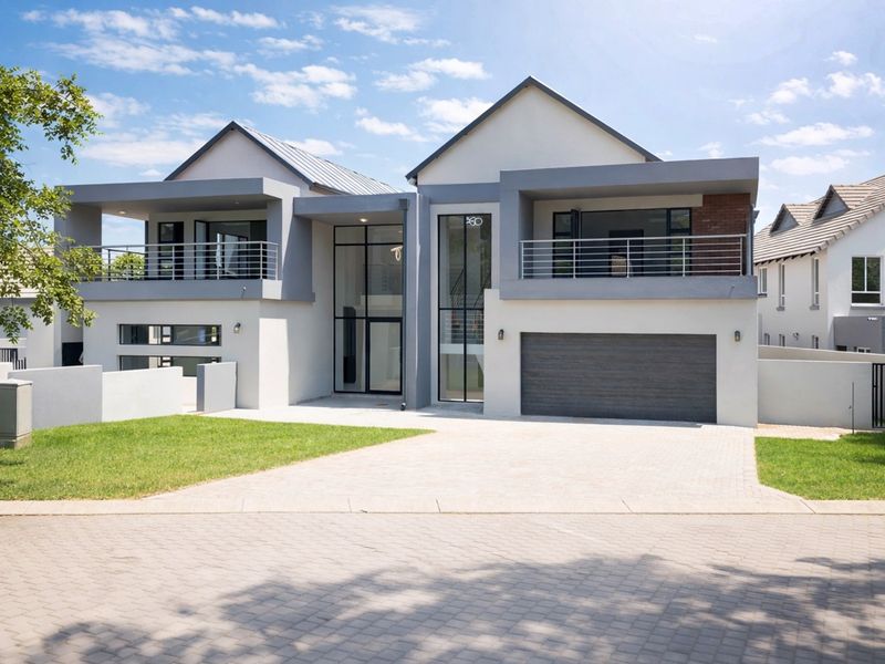 Modern double-story residential home featuring a paved driveway, double garage, and upper-level balconies with contemporary architectural design.