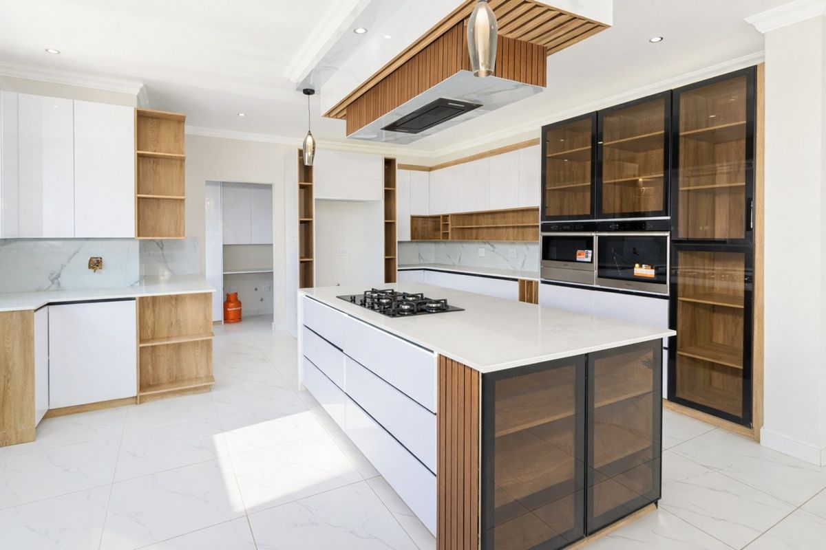 Modern kitchen featuring a central island with gas hob, high-end cabinetry, stone countertops, and integrated appliances in a bright, open-plan layout.
