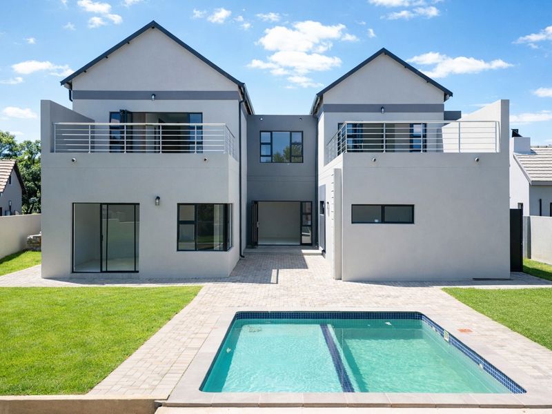 Modern double-story rear elevation featuring a swimming pool, paved patio area, and upper-level balconies with metal railings.