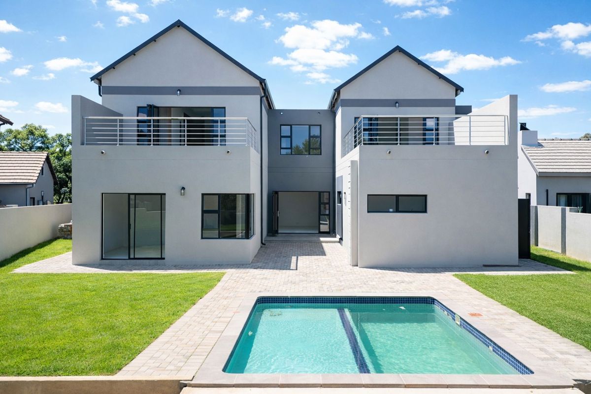 Modern double-story rear elevation featuring a swimming pool, paved patio area, and upper-level balconies with metal railings.
